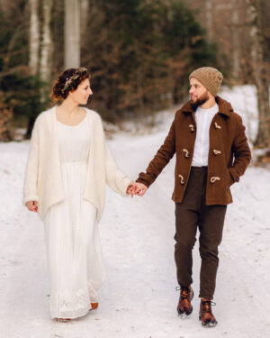 couple de mariés marchant dans la neige en forêt au Moulin Bas