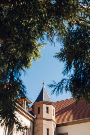 orangerie du manoir à Oberhaslach en Alsace, architecture avec tourelle et toit en tuiles vue à travers les arbres